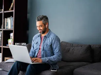 Man sitting on his couch typing on his laptop